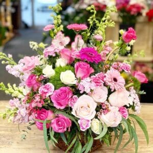 A vibrant bouquet of pink and white flowers in a rustic basket.