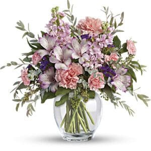 Elegant bouquet of pink carnations and purple flowers in a glass vase.
