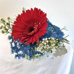 Red gerbera with blue filler and white waxflowers